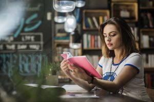 foto de menina lendo uma revista escolar na biblioteca