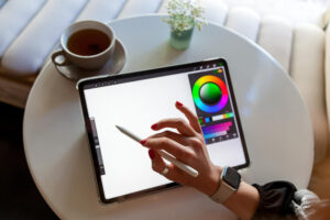 Pessoa usando caneta digital em tablet com aplicativo de desenho aberto, exibindo seletor de cores.