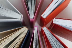 Vista superior de vários livros dispostos em círculo, com capas coloridas em vermelho, rosa, azul e branco.